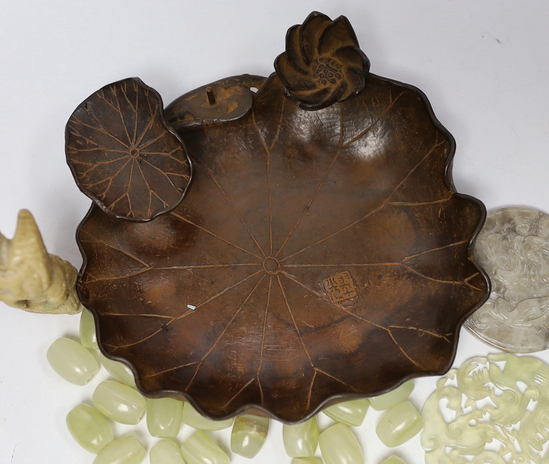 A collection of Chinese items including a bronze tray in the form of a water lily, two bowenite or jadeite discs, a soapstone cat and a bag of hardstone beads, bronze 14cm diameter